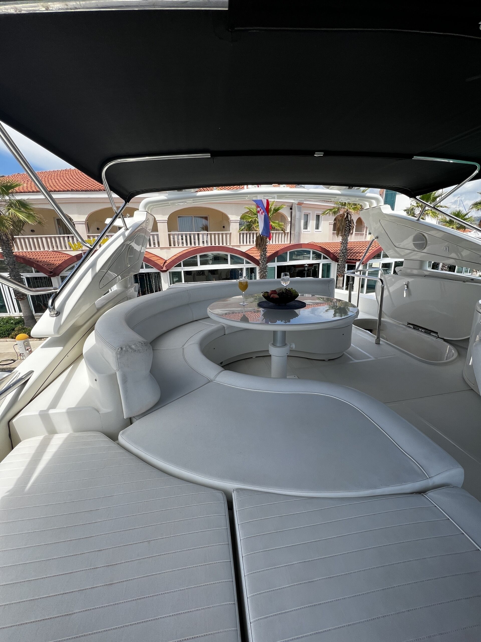 Le pont d’un yacht, avec une table ronde, des sièges rembourrés et un drapeau.