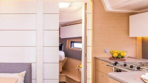 Interior compacto de uma motorhome, com cozinha compacta, área de estar com almofadas e uma pequena janela.