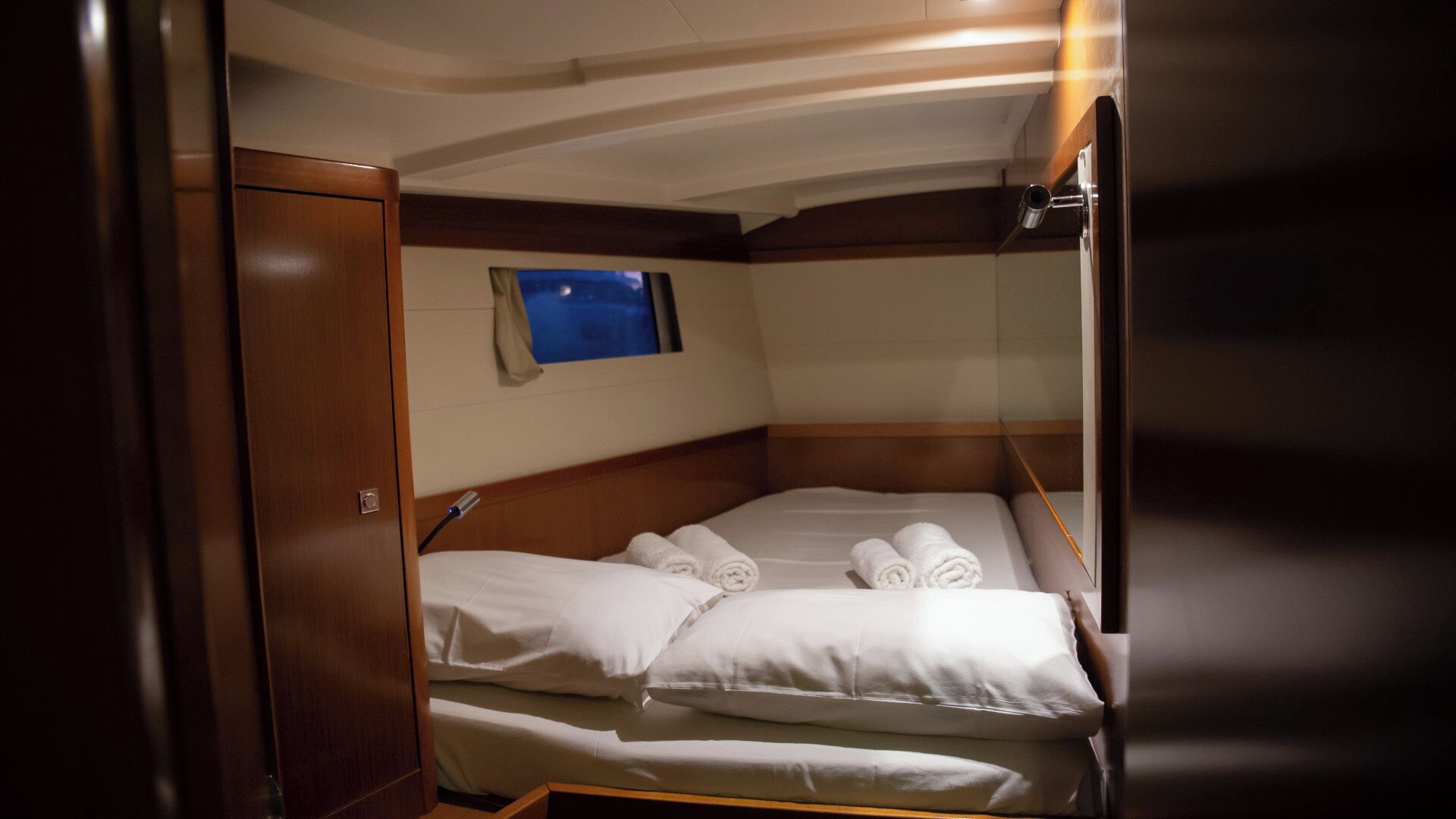A compact cabin with a bunk bed, a small window, and a view of the night sky.
