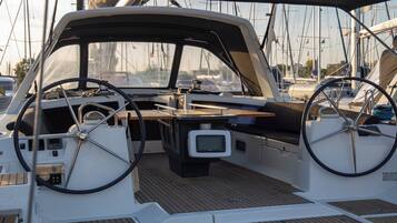 Das Deck eines Bootes mit Steuerpult, kleinem Tisch und fest installiertem Fernseher.