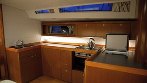 Cucina compatta con mobili in legno, un lavello, un fornello e un frigorifero.