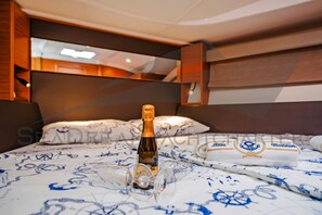 A bed with a bottle of champagne, glasses, and a towel with a nautical design. - Sun-Kissed Sailing Adventure in Zadar, Croatia (Bibinje)