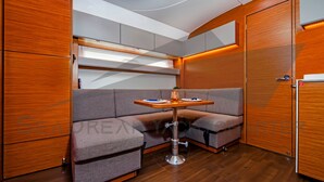 A compact, modern interior with a wooden floor, a cushioned seating area, a small table, and built-in cabinets. - Sun-Kissed Sailing Adventure in Zadar, Croatia (Bibinje)