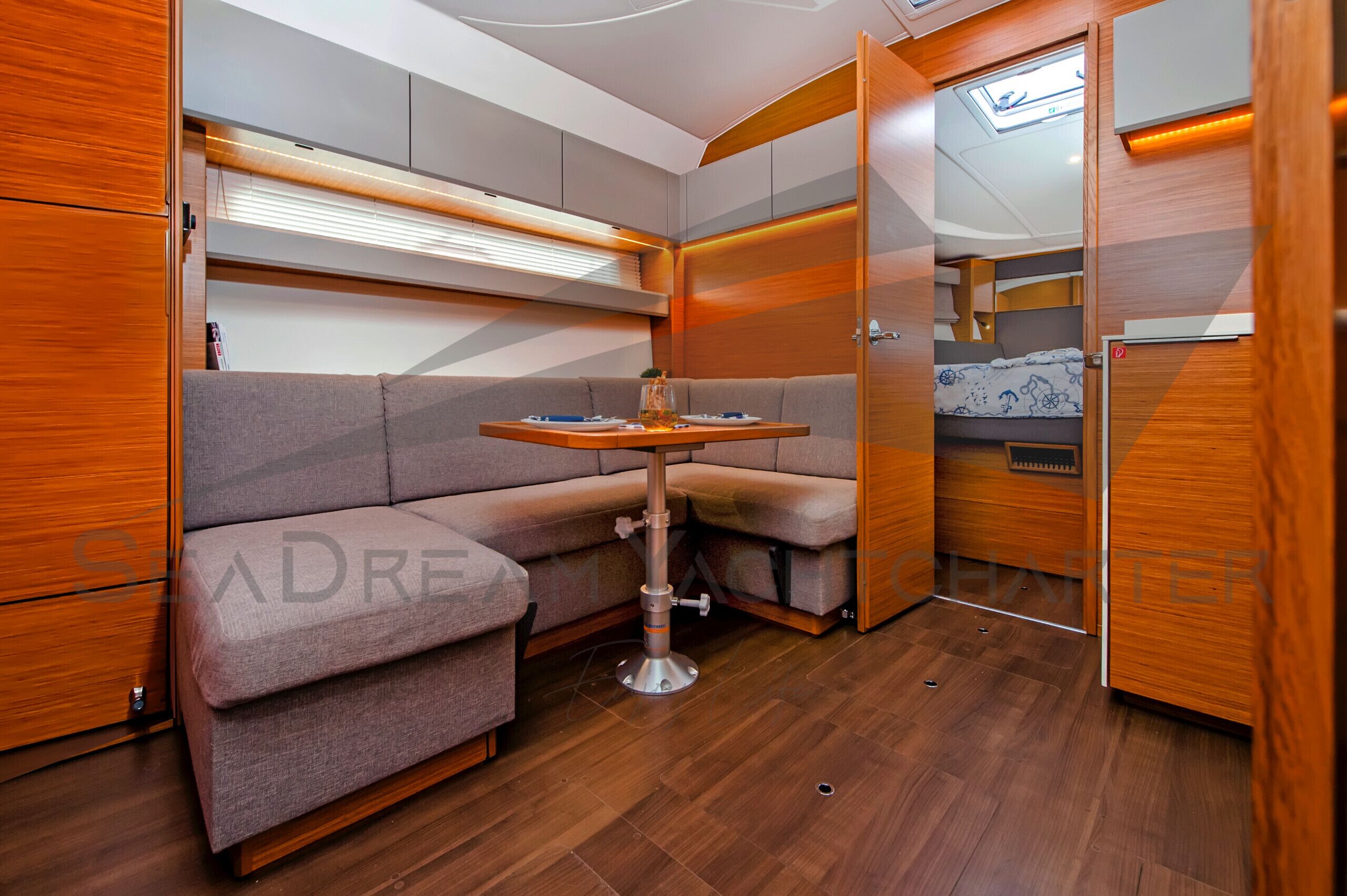 A compact RV interior with a sofa, table, and storage cabinets.