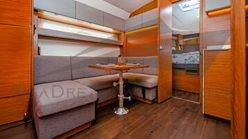 A compact RV interior with a sofa, table, and storage cabinets.