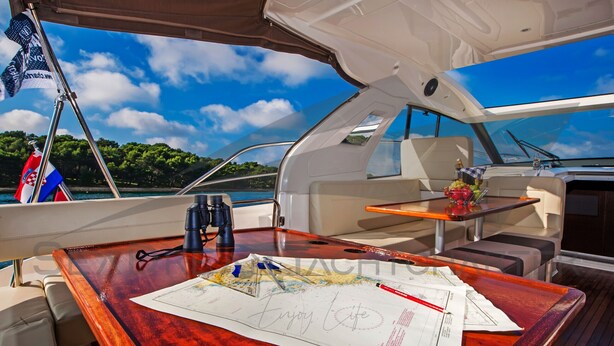 A boat interior with a dining area, a map, and a flag. - Sun-Kissed Sailing Adventure in Zadar, Croatia (Bibinje)