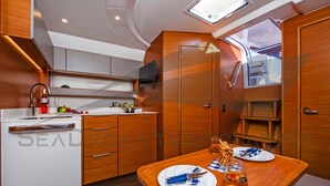 A compact kitchen with a dining area, wooden cabinetry, a built-in TV, and a small window. - Sun-Kissed Sailing Adventure in Zadar, Croatia (Bibinje)
