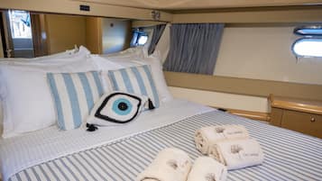 Una cama con ropa de cama a rayas, un cojín decorativo y toallas enrolladas con texto.