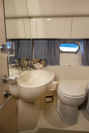 Ein Badezimmer mit Waschbecken, Toilette und einem Fenster mit Vorhängen.