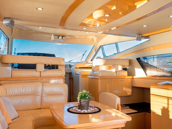 A yacht interior with a dining area, seating, and a potted plant.