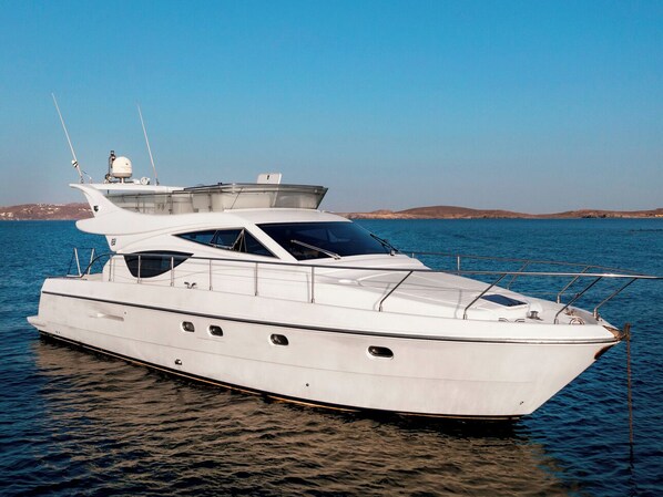 A white yacht with a cabin, a covered deck area, and a helipad.