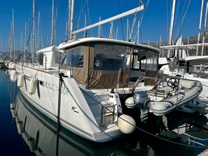 Een jachthaven met aangemeerde boten, waaronder een witte boot met een kajuit en een kleinere motorboot.