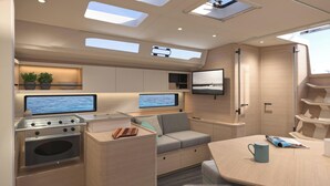 A compact kitchen with a stove, two monitors, a sofa, and a dining table.