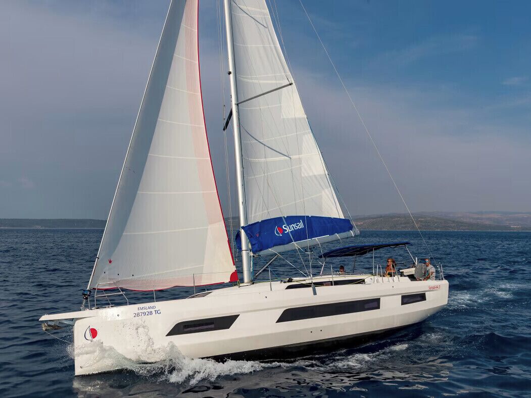 Eine Segelyacht mit weißem Rumpf und blauen Segeln, genannt 'Sunsail', auf dem Wasser.