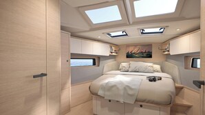 A compact, well-lit bedroom with a bed, skylights, and a painting on the wall.