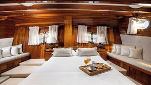 Una cabina con un letto, due divani, un vassoio con articoli per la colazione e una finestra con tende.