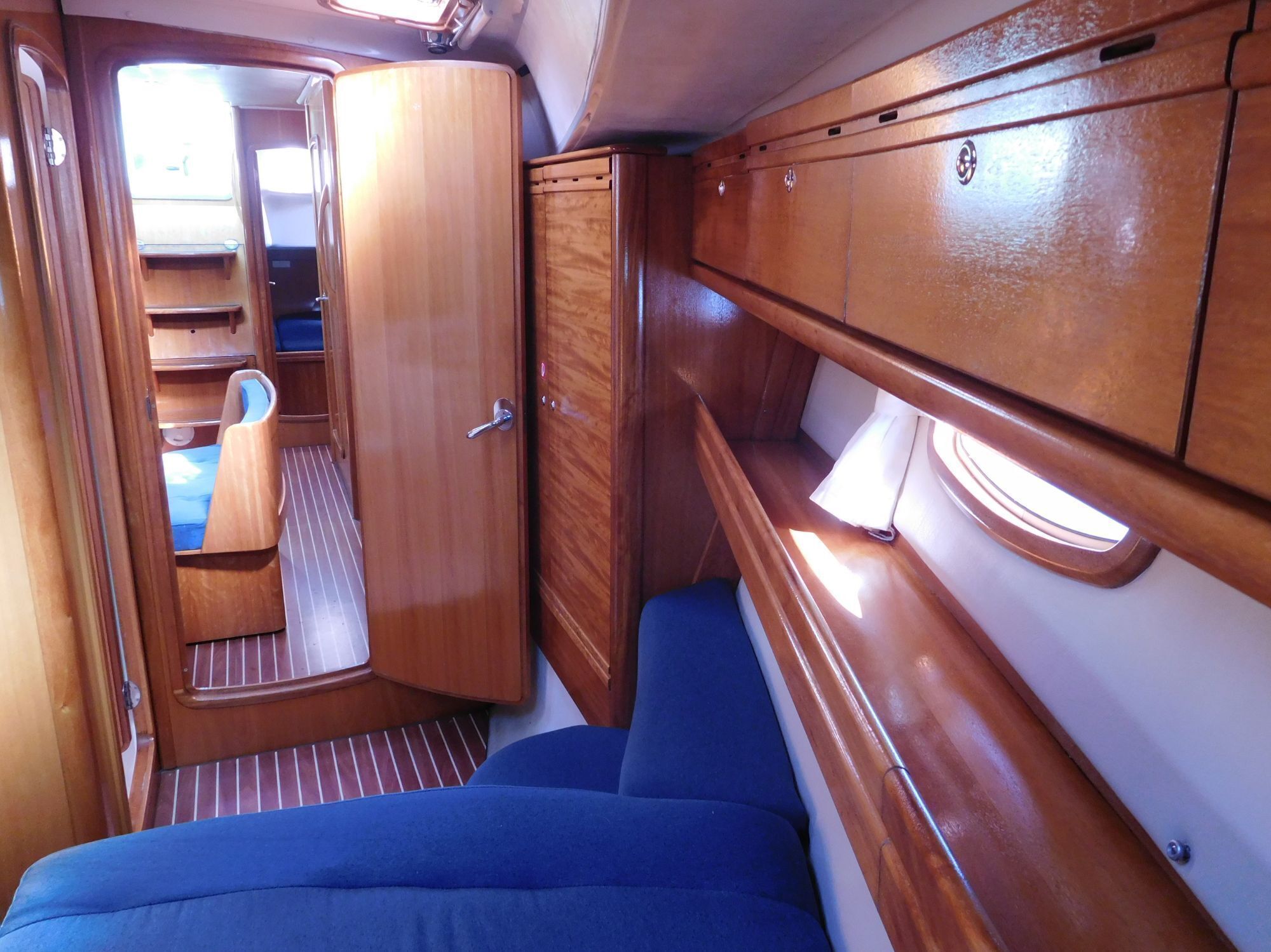 Een compact interieur met een bed, een klein zitgedeelte en houten kastjes.