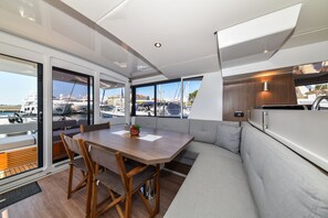 Un interior moderno con comedor, asientos y vista al puerto deportivo.