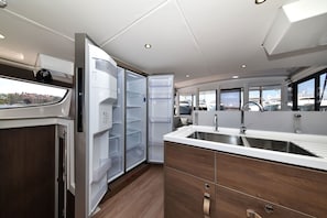 Eine kleine Küche mit integriertem Kühlschrank, einem Spülbecken und einem Fenster mit Blick auf eine Marina.