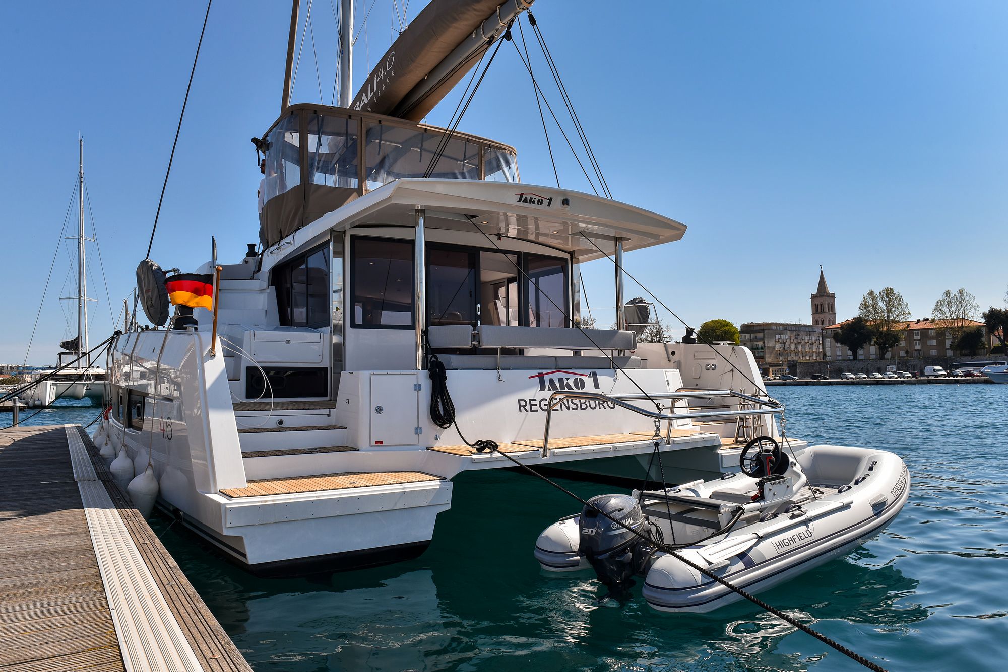 A white yacht docked at a marina with a clear view of a historic building in the background.