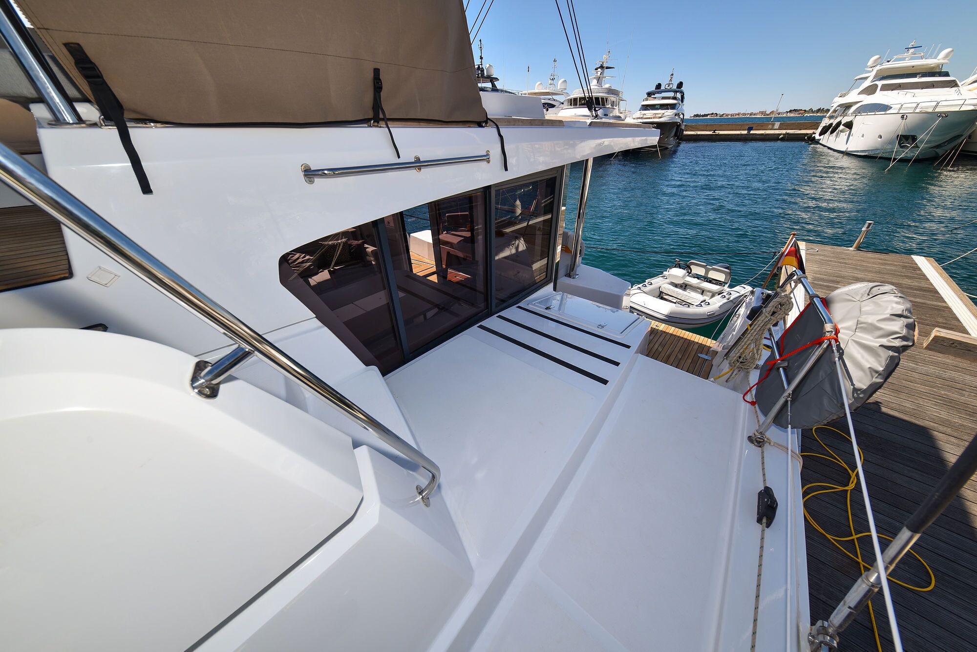 A yacht's deck with a seating area, a small table, and a view of the marina.