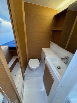 A compact bathroom with a toilet, sink, and wooden cabinetry. - Sun-Kissed Sailing Adventure in Sibenik, Croatia (Rogoznica)