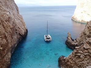 A boat anchored in a clear blue sea between rocky cliffs. - Sun-Kissed Sailing Adventure in Islas Cícladas, Mykonos (Mykonos)