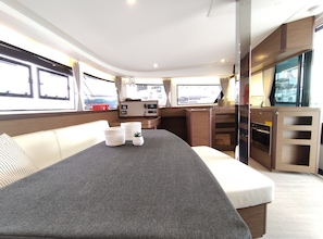 Un interior moderno con un sofá, una mesita, una zona de cocina y un ventanal con vistas al exterior.