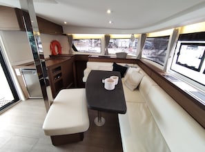 Un interior moderno y funcional con comedor, asientos y una pequeña kitchenette.