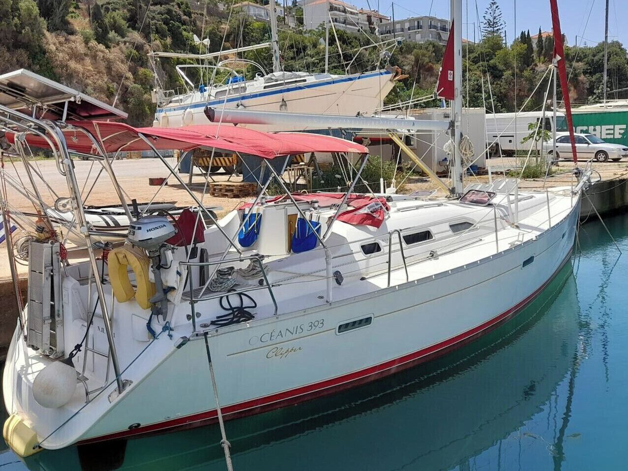 Un voilier était amarré dans une marina. Il était doté d’un auvent rouge, d’une coque blanche et portait le nom « CÉANIS 393 » sur son flanc.