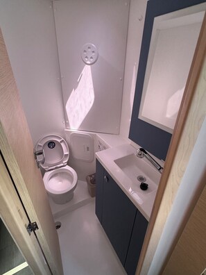A compact bathroom with a toilet, sink, and mirror. - Sun-Kissed Sailing Adventure in Zadar, Croatia (Bibinje)
