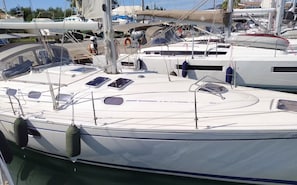 Eine Segelyacht liegt im Hafen festgemacht, mit sauberem Deck, mehreren Fenstern und einem Rettungsring.