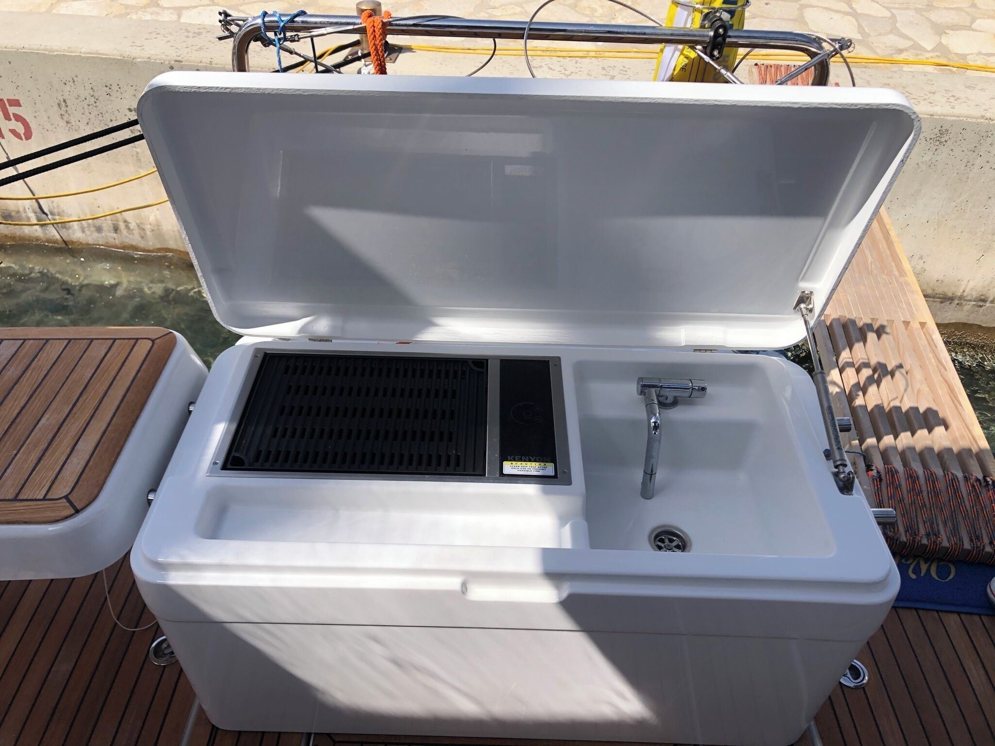 An open cooler with a built-in sink, located on a wooden deck.