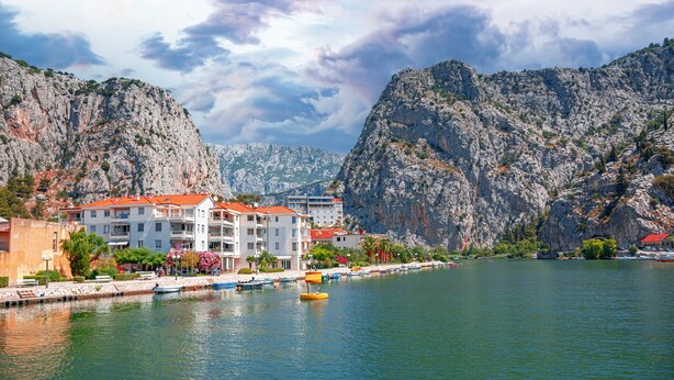 A coastal town with buildings along the waterfront, a marina with boats, and rocky cliffs in the background. - Sun-Kissed Sailing Adventure in Split-Dalmacia, Croatia (Omiš)