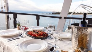 A table set with plates, cutlery, glasses, and a seafood platter on a boat deck with a view of the water. - Sun-Kissed Sailing Adventure in Split-Dalmacia, Croatia (Omiš)