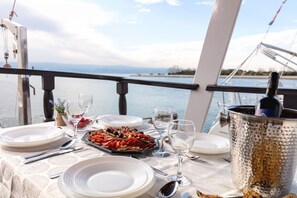 A table set with plates, cutlery, glasses, and a seafood platter on a boat deck with a view of the water. - Sun-Kissed Sailing Adventure in Split-Dalmacia, Croatia (Omiš)