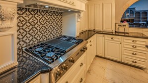 A kitchen with a gas stove, white cabinetry, a patterned backsplash, and marble flooring. - Casa de Valdes: Spacious Two-Story Home Near SeaWorld and Military Bases (San Antonio)