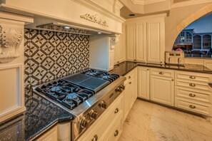 A kitchen with a gas stove, white cabinetry, a patterned backsplash, and marble flooring. - Casa de Valdes: Spacious Two-Story Home Near SeaWorld and Military Bases (San Antonio)