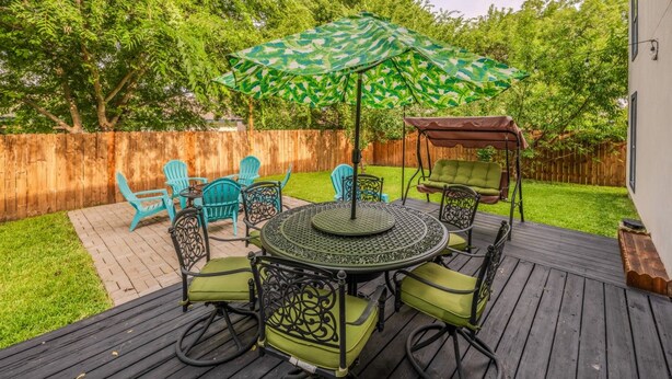 A deck with a round table, chairs, and an umbrella. - Casa de Valdes: Spacious Two-Story Home Near SeaWorld and Military Bases (San Antonio)