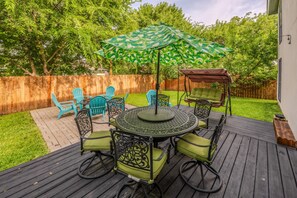 A deck with a round table, chairs, and an umbrella. - Casa de Valdes: Spacious Two-Story Home Near SeaWorld and Military Bases (San Antonio)