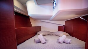A compact, well-lit cabin with a single bed, pillows, and neatly rolled towels. - Sun-kissed Sailing Adventure in the Ionian Islands (Preveza)