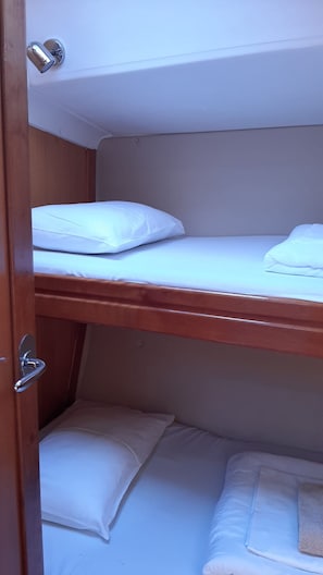 Ein Etagenbett mit weißer Bettwäsche und einem Holz-Kopfteil.