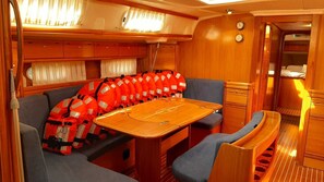 A compact interior with a wooden table, cushioned seating, and a row of life jackets. - Sun-kissed Sailing Adventure in Split-Dalmatia, Croatia (Trogir)