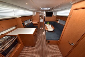 A compact boat interior with a kitchenette, seating area, and a small table with a plant. - Sun-Kissed Sailing Adventure in Zadar, Croatia (Bibinje)