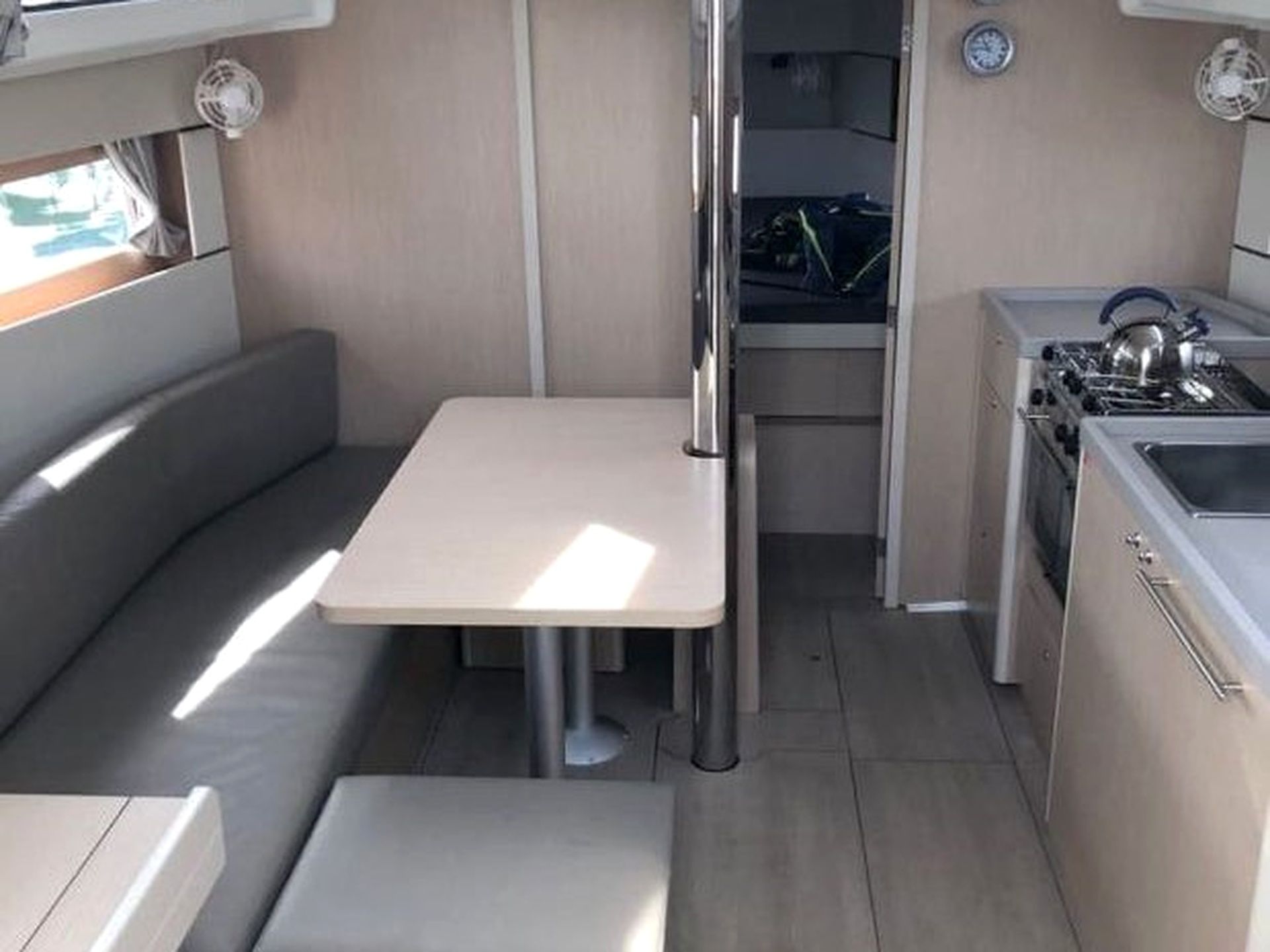 Een ruimtelijk keukenhoekje met een kookplaat, spoelbak en een klein eethoekje met een tafel en bank.