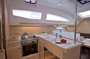 Une petite cuisine fonctionnelle, avec un fourneau, un four et un évier, ainsi qu’un coin repas comprenant une table et des chaises.
