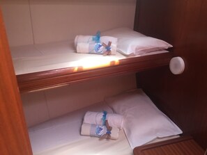 Habitación de hotel con dos camas, cada una con una almohada y una toalla enrollada.