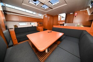 Eine schmale Kombüse mit einem zentralen Tisch und Sitzgelegenheiten, Oberlichtern und einer kleinen Küchenzeile.