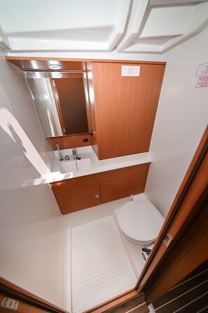 Et lille badeværelse med en trævægskonsol, en vask, et spejl og et toilet.