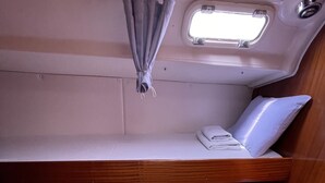 Une petite cabine équipée de deux lits superposés, d’une petite fenêtre et d’un banc en bois.